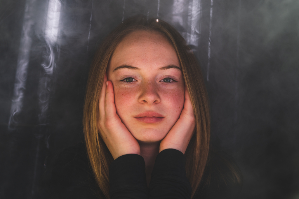 Helen resting her face on her hands inside a softly lit box.