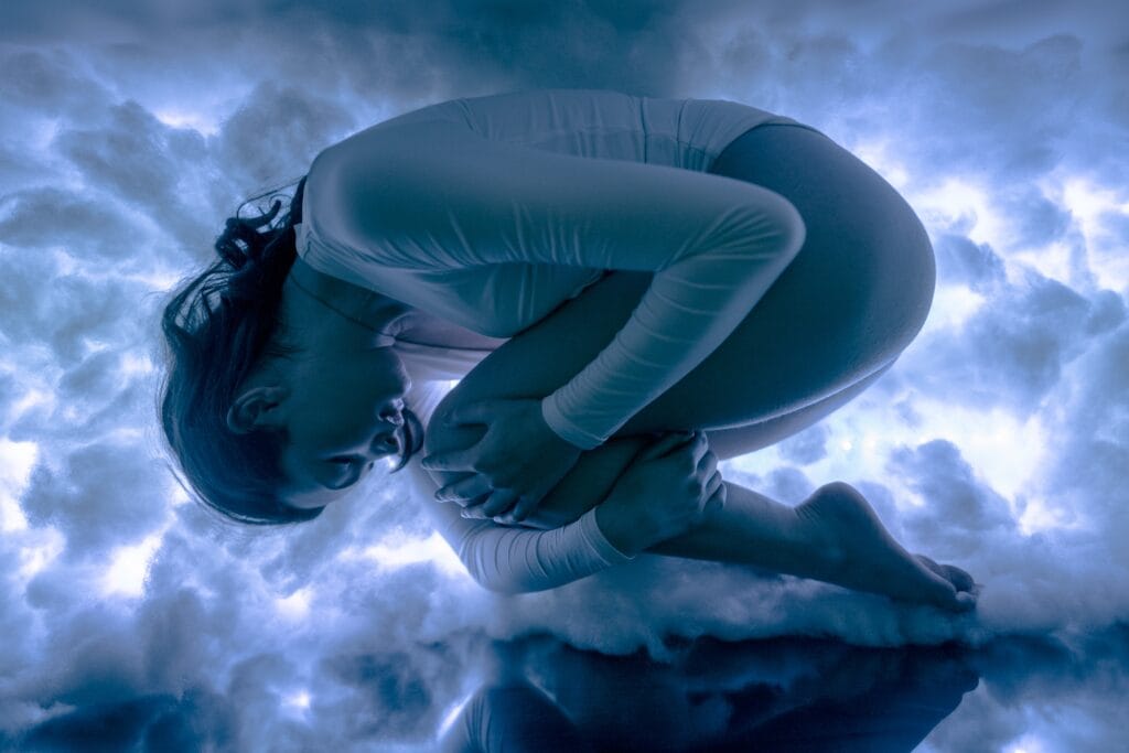 Alyssa curled into a sculptural pose among glowing blue clouds.