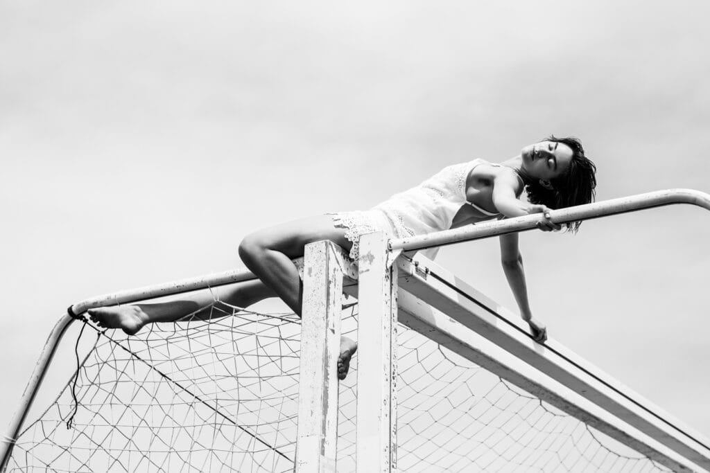 Black and white portrait of Helen stretched across the frame of a soccer goal.