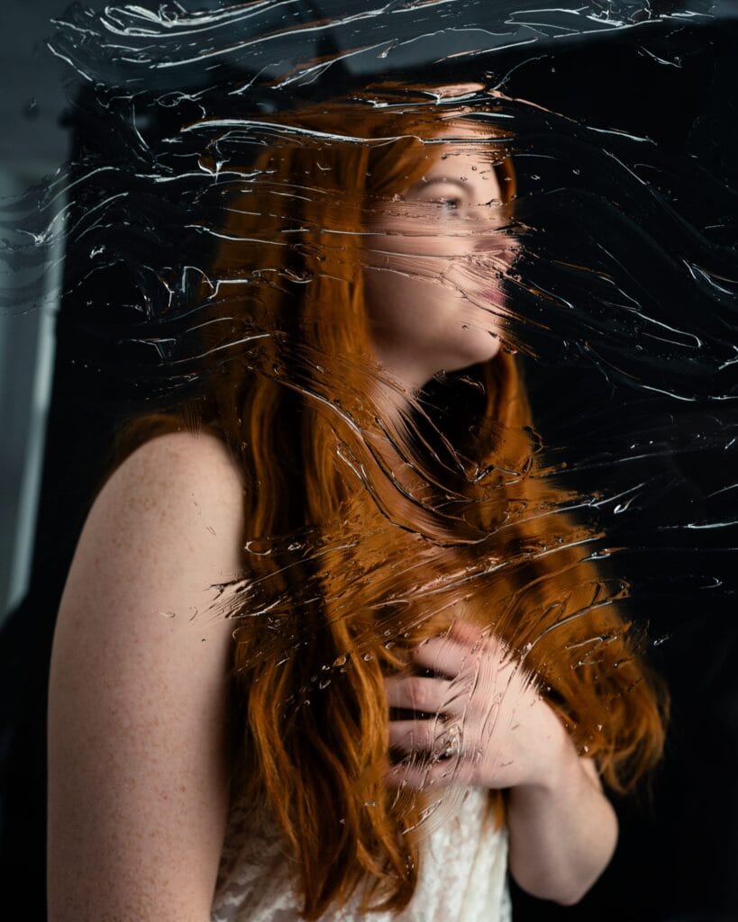 Elizabeth in profile, her red hair and face refracted through a textured transparent surface.
