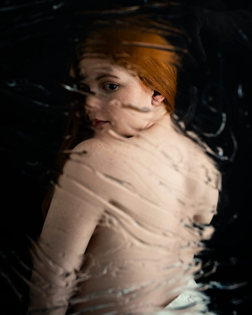 Elizabeth looks back over her shoulder through curved streaks of optical distortion.