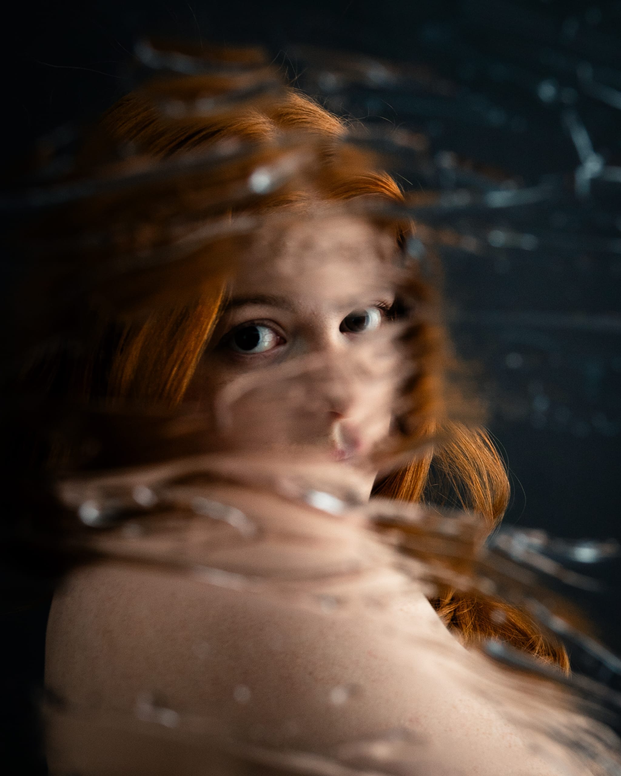 A close portrait of Elizabeth’s eyes and red hair through a blurred, textured surface.