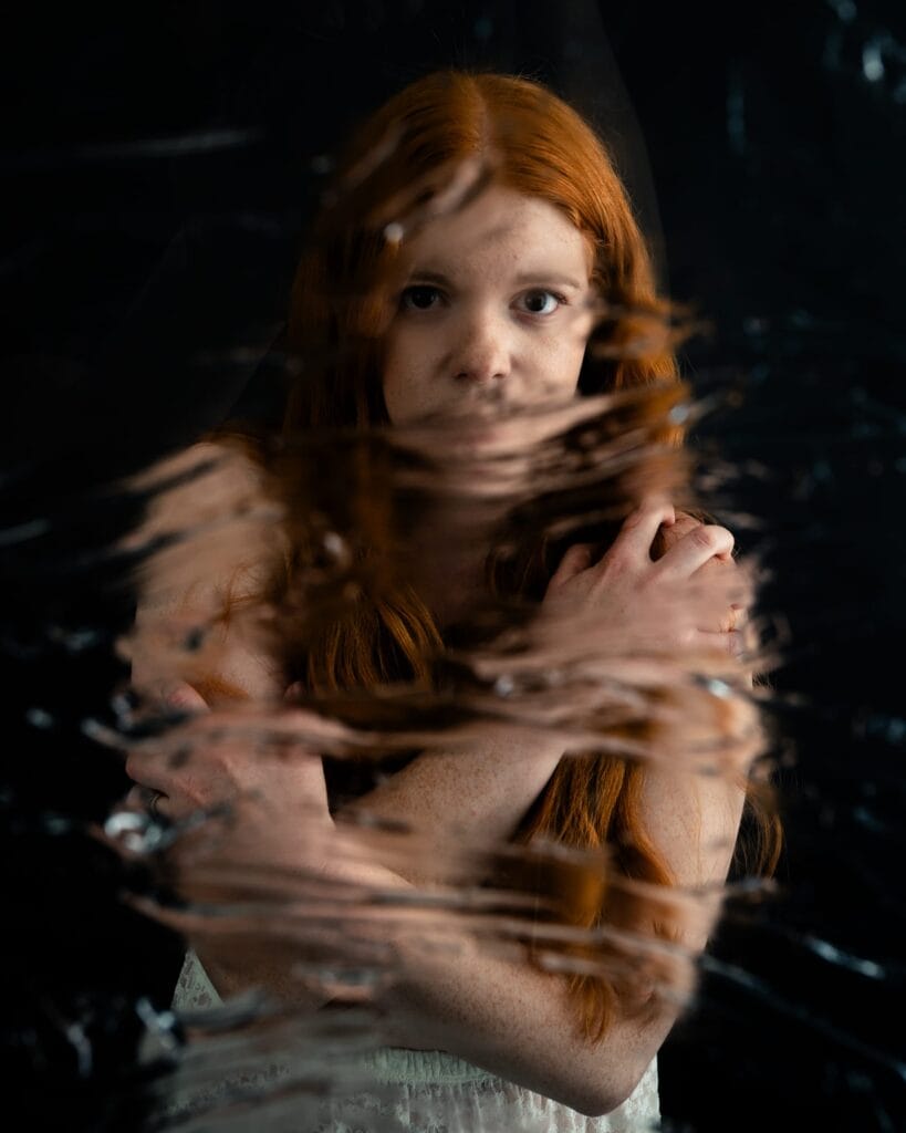Elizabeth faces the camera with her arms crossed over her shoulders behind streaks of distortion.