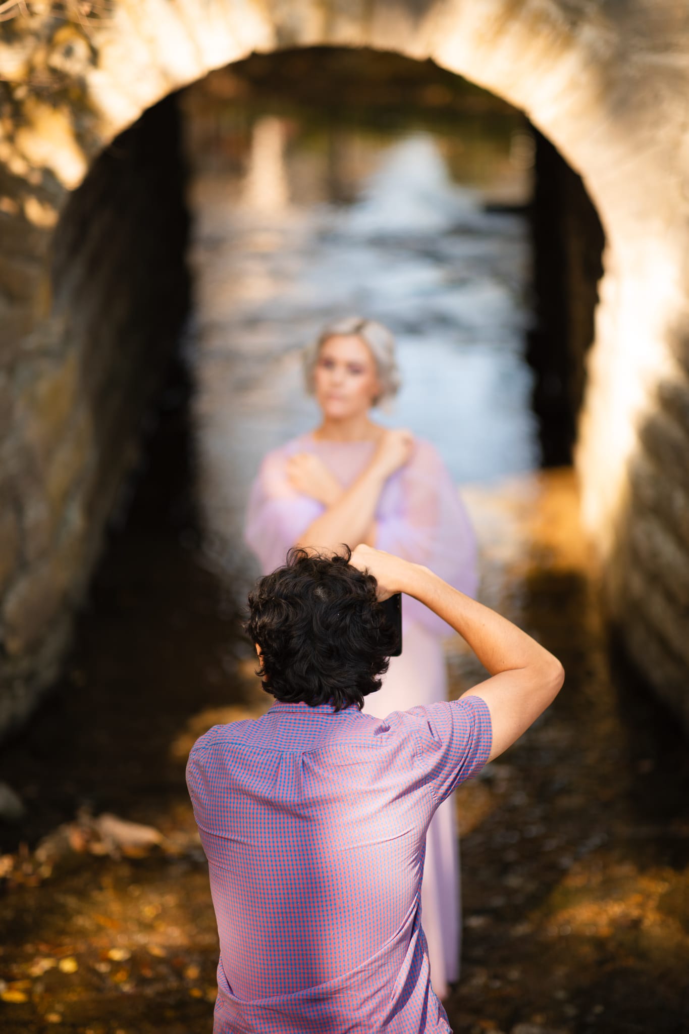 Daniel O'Donnell photographing a model in a sunlit stone archway.