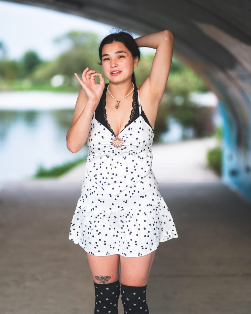 Reese makes a playful expression with one hand beside her face beneath the bridge.