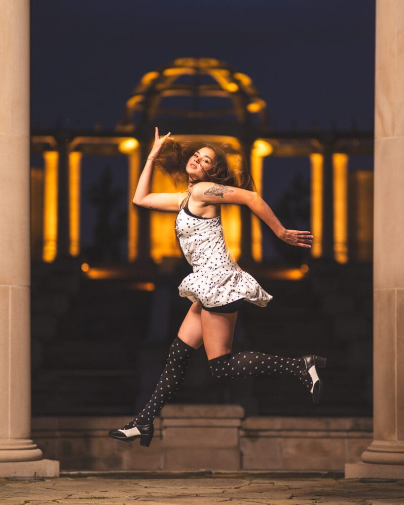 Reese leaps between stone columns with warm lights glowing behind her.