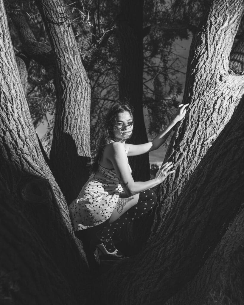 Black-and-white portrait of Reese perched between the trunks of a large tree.
