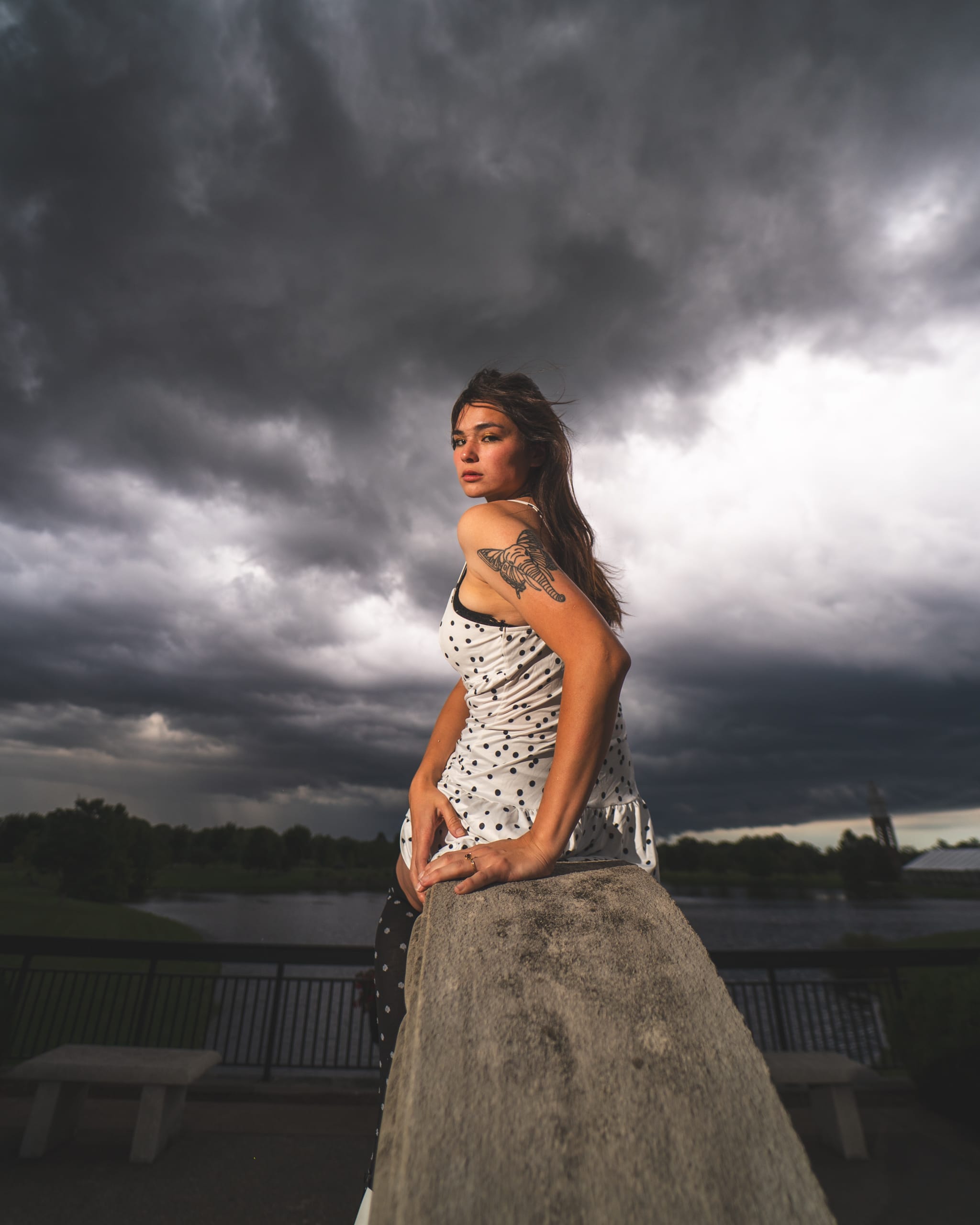 Reese looks over her shoulder while sitting beneath dramatic storm clouds.