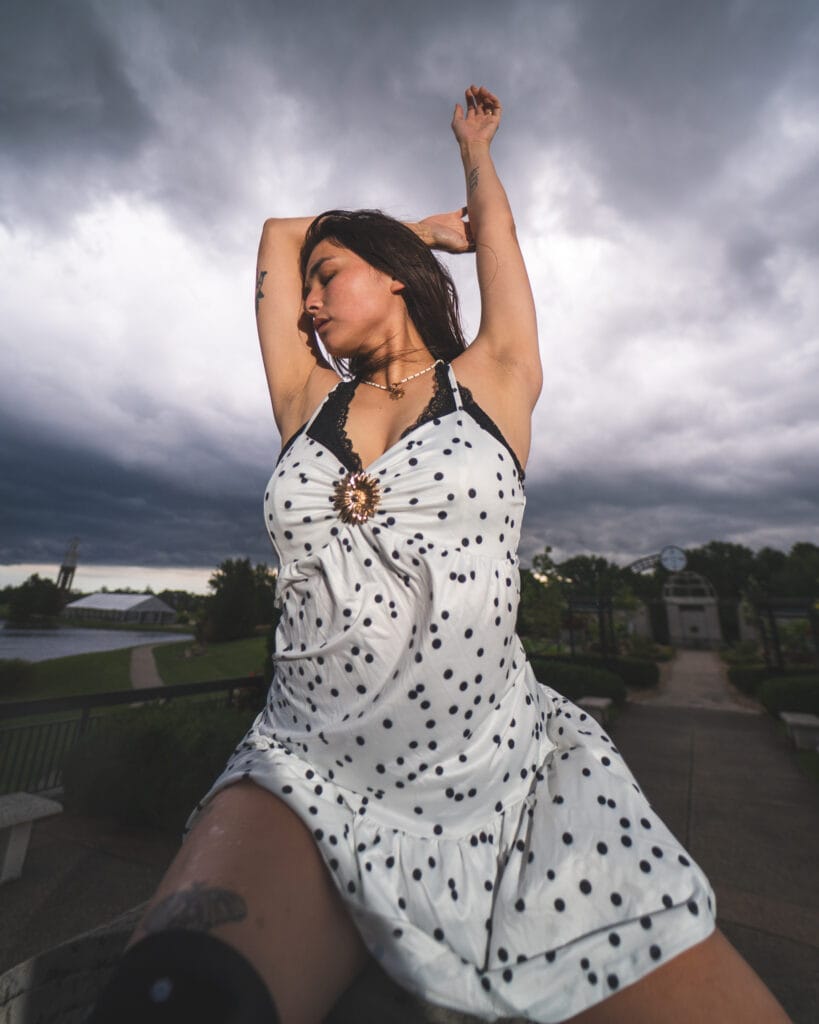 Reese raises one arm as the wind lifts her polka-dot dress.