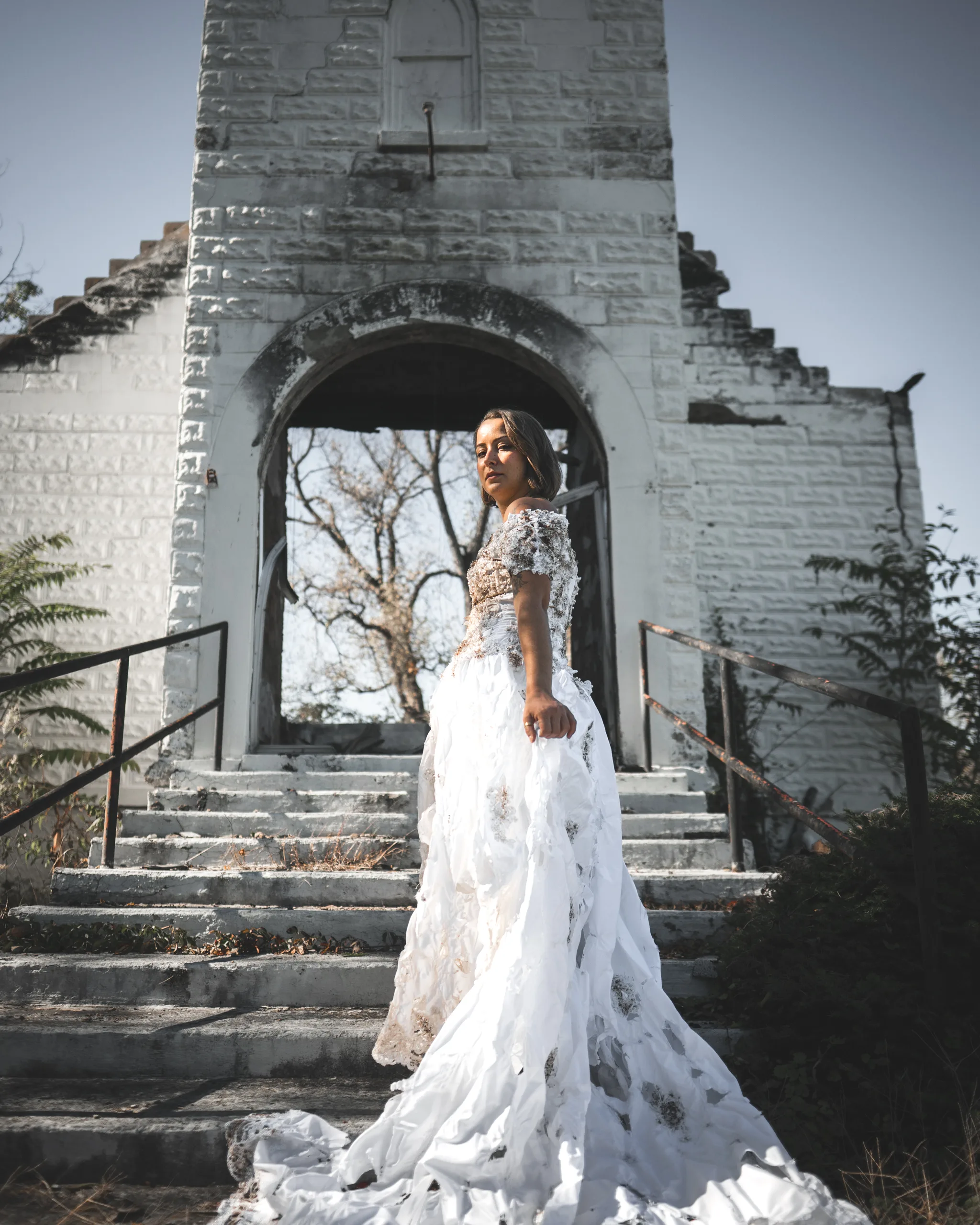 Kaitlyn looks back toward the camera on the church steps, wearing the distressed wedding dress.