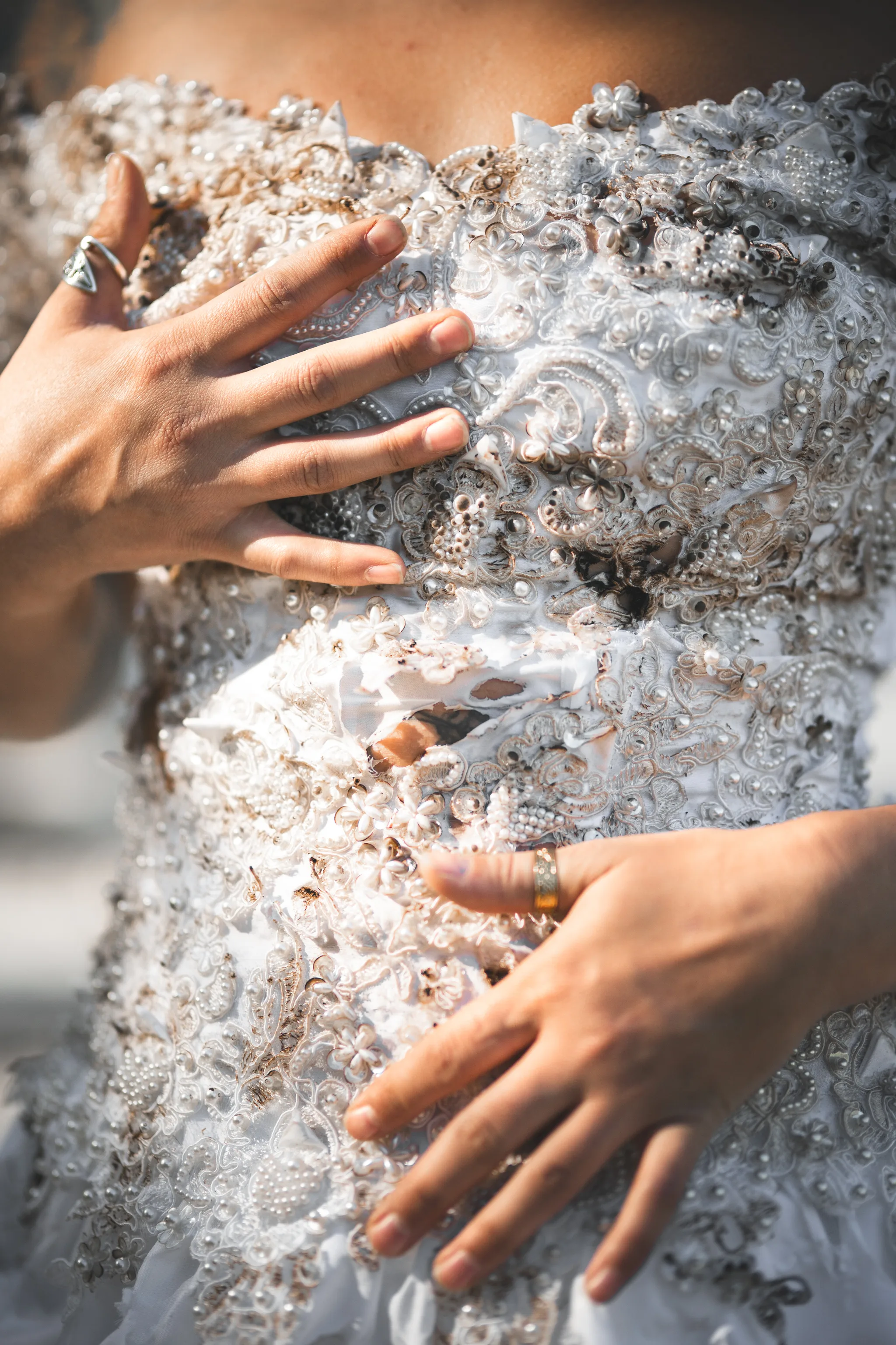 Close detail of Kaitlyn’s hands and the stained, distressed lace and beadwork of the vintage wedding dress.